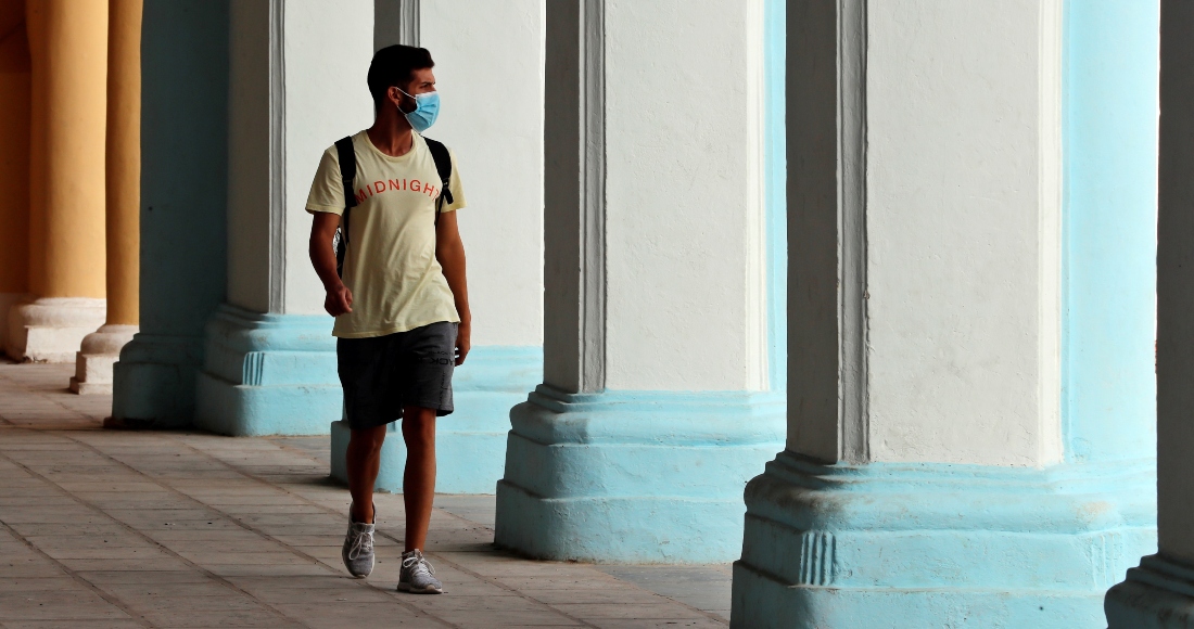 Un joven camina con mascarilla por unos portales en La Habana Vieja (Cuba).