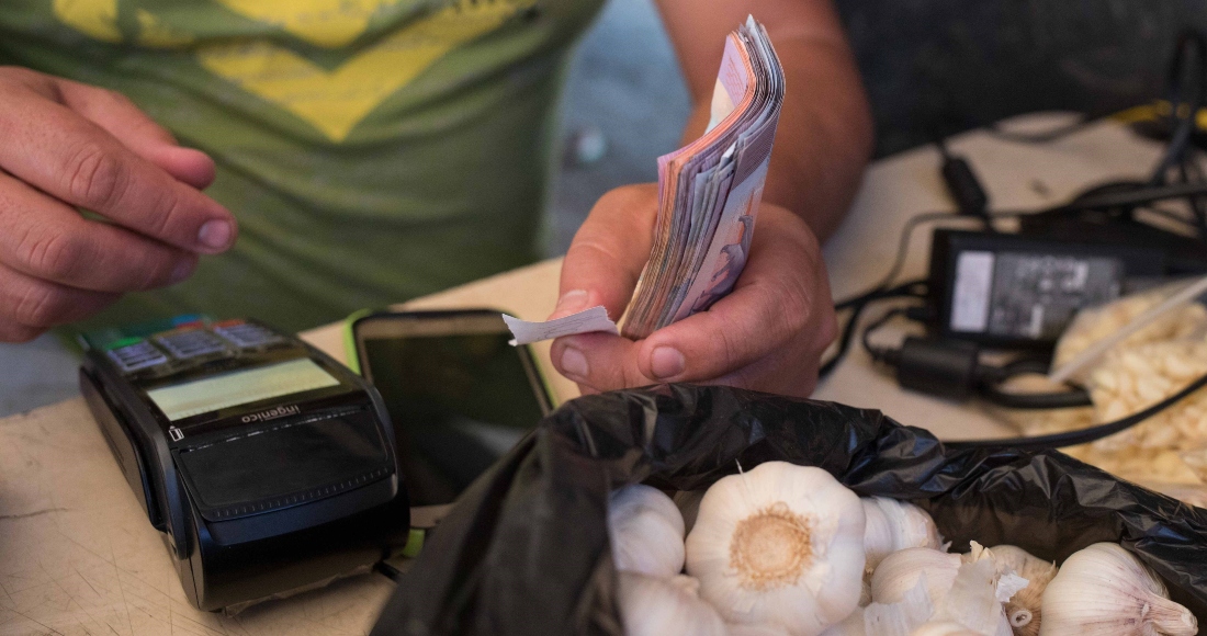 Fotografía de archivo en la que se registraron las manos de un vendedor de verduras al cobrar con un datáfono, en Caracas (Venezuela).