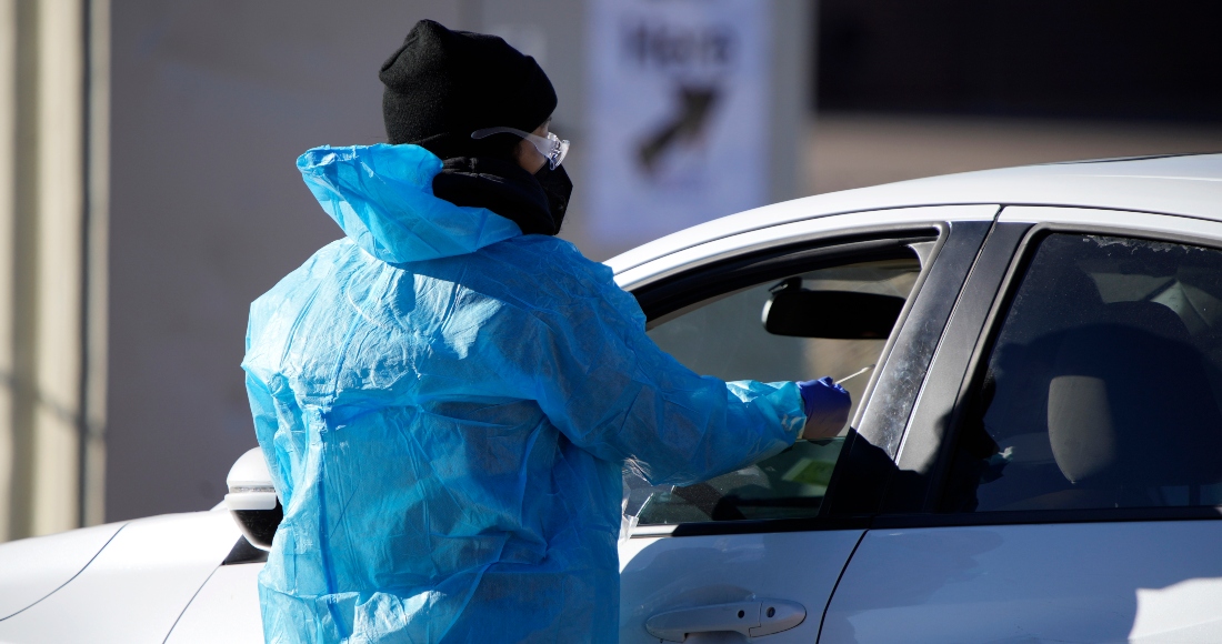 Médico realiza una prueba de hisopado nasal a un automovilista que hace cola en una fila en un sitio de prueba de COVID-19 cerca del All City Stadium el 30 de diciembre de 2021, en el sureste de Denver.