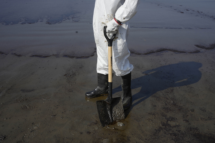 Un trabajador hace una pausa en la playa Cavero durante la limpieza de petróleo en Ventanilla, Callao, Perú, el martes 18 de enero de 2022, luego de que las altas olas atribuidas a la erupción de un volcán submarino en Tonga provocaran un derrame de petróleo.