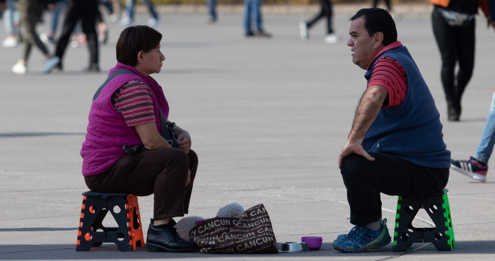 Una pareja de tercera edad aprovecha la sombra de la asta de la bandera en el Zócalo capitalino para tomar un descanso y charlar.