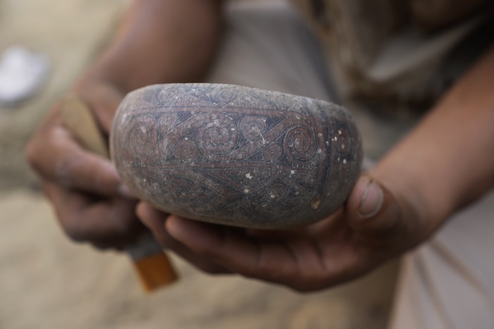 Un arqueólogo limpia una vasija en el sitio donde se encontraron seis momias de niños en Cajamarquilla, cerca de Lima, Perú, el domingo 13 de febrero de 2022.