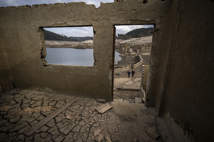 Jose Penín, de 72 años, camina con su hermano Julio, de 78, mientras visitan el antiguo pueblo de Aceredo, sumergido hace tres décadas cuando una presa hidroeléctrica inundó el valle y ahora accesible debido a la sequía en el embalse de Lindoso, en el noroeste de España, el viernes 11 de febrero de 2022. Los tejados asomando en el agua se han convertido en una escena habitual en verano en el embalse de Lindoso, en el noroeste de España.