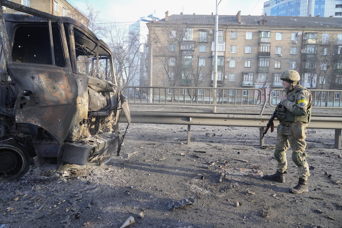 Un soldado ucraniano camina frente a un vehículo militar quemado, el sábado 26 de febrero de 2022, en Kiev, Ucrania.