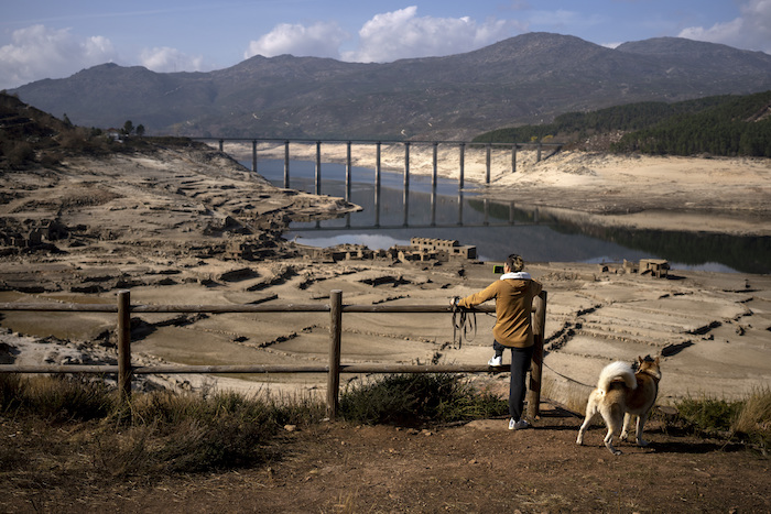 Un hombre fotografía el antiguo pueblo de Aceredo, sumergido hace tres décadas cuando una represa hidroeléctrica inundó el valle, y que ahora queda al descubierto debido a la sequía, en el embalse de Lindoso, en el noroeste de España, el sábado 12 de febrero de 2022.