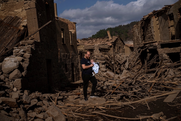 Rafael Monlina, de 33 años, sostiene a su hijo de cuatro meses, Marcos, mientras visitan el antiguo pueblo de Aceredo, sumergido hace tres décadas cuando una presa hidroeléctrica inundó el valle, emerge debido a la sequía en el embalse de Lindoso, en el noroeste de España, el sábado 12 de febrero de 2022.