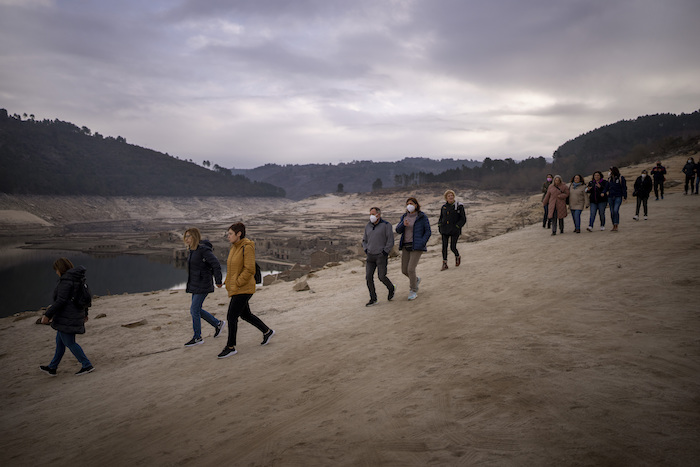 Vecinos de la zona caminan durante una visita al antiguo pueblo de Aceredo, accesible debido a la sequía en el embalse de Lindoso, en el noroeste de España, el sábado 12 de febrero de 2022.