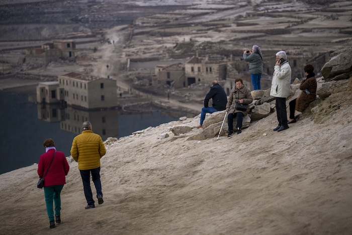 Visitantes miran al antiguo pueblo de Aceredo, visible debido a la sequía, en el embalse de Lindoso, en el noroeste de España, el sábado 12 de febrero de 2022.