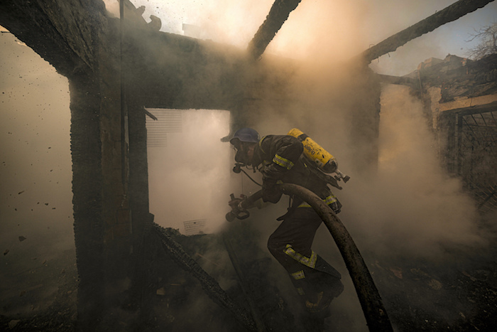 Un bombero ucraniano rocía agua en una casa destruida por un ataque de artillería en Kiev, Ucrania, el miércoles 23 de marzo de 2022.