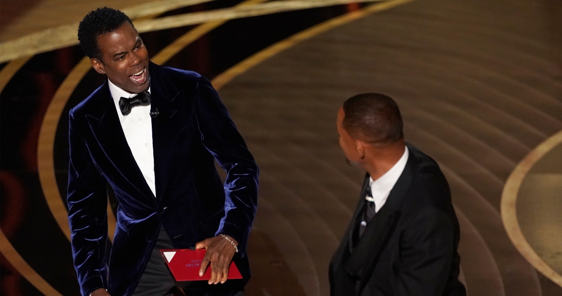 El presentador Chris Rock, a la izquierda, reacciona tras ser confrontado por Will Smith mientras presentaba el premio al Mejor Documental en la ceremonia de los Óscar, tras hacer un chiste sobre su esposa, Jada Pinkett Smith, el domingo 27 de marzo de 2022 en el Teatro Dolby en Los Ángeles.