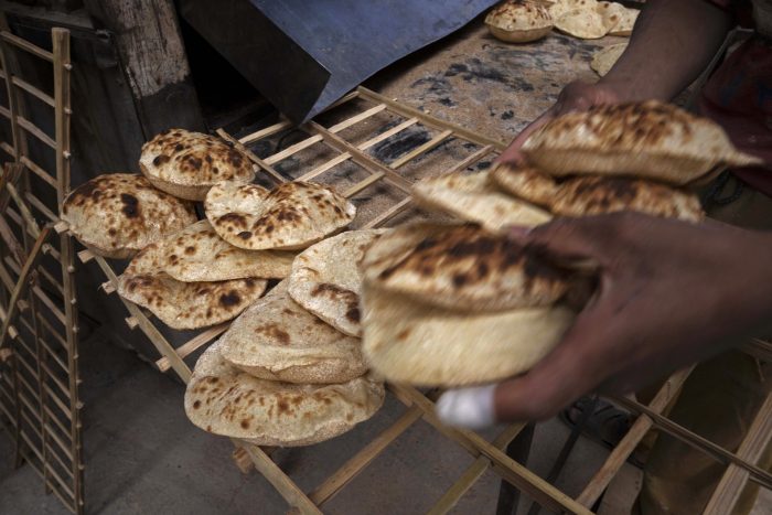 Un trabajador recoge los tradicionales panes egipcios conocidos como baladi en una panadería en El-Sharabia, en el distrito Shubra de El Cairo, Egipto, el miércoles 2 de marzo de 2022. Los tanques y misiles rusos que asedian Ucrania también amenazan el suministro de comida y los medios de vida de personas en Europa, África y Asia.