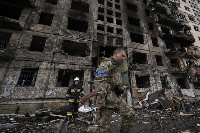 Soldados y bomberos ucranianos buscan en un edificio derruido tras un ataque en Kiev, Ucrania, el lunes 14 de marzo de 2022.