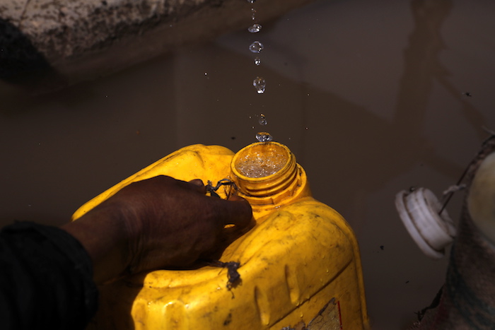 Una Mujer Recolecta Agua En Un Recipiente En Una Fotografía De Archivo