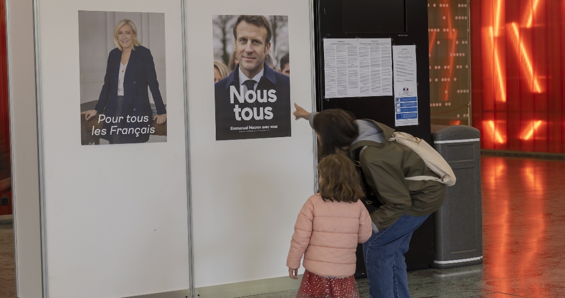 Un votante muestra a su hija los carteles electorles de los candidatos a la Presidencia francesa.