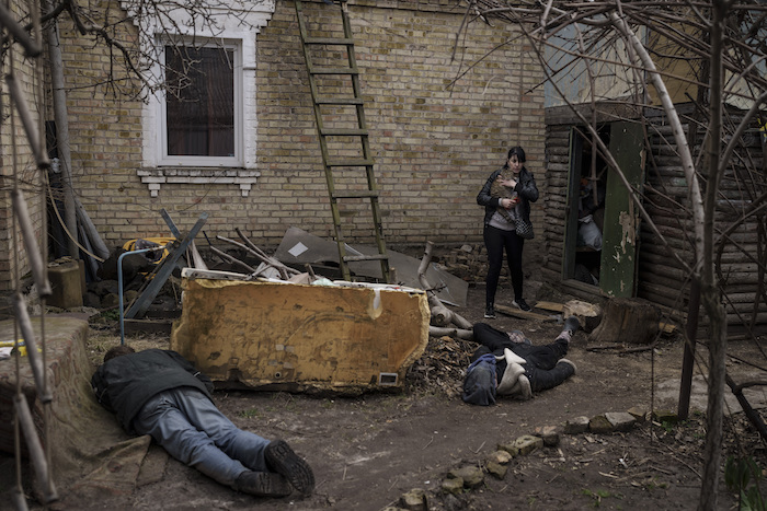 Ira Gavriluk carga a su gato mientras pasa cerca de los cadáveres de su esposo, su hermano y otro hombre, los cuales fueron asesinados en el exterior de su casa, el lunes 4 de abril de 2022, en Bucha, en las afueras de Kiev, Ucrania.