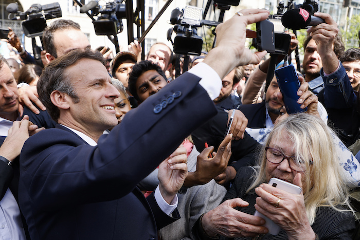 El Presidente francés y candidato presidencial centrista Emmanuel Macron se toma una selfie con residentes durante una escala de campaña el jueves 21 de abril de 2022 en Saint-Denis, en las afueras de París.