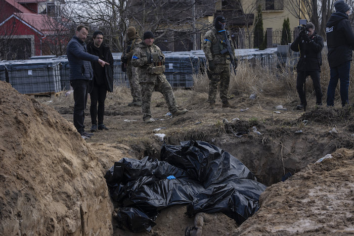 Un grupo de personas observa una fosa común el lunes 4 de abril de 2022, en Bucha, en las afueras de Kiev, Ucrania.