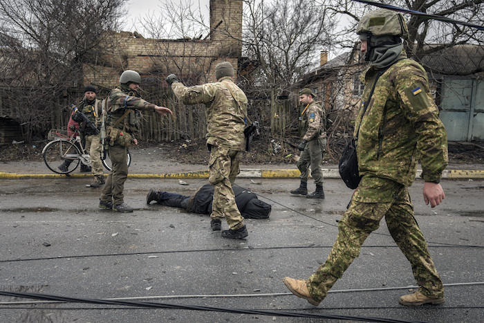 Soldados ucranianos atan el cadáver de un civil a un cable y revisan que no tenga trampas explosivas en el suburbio Bucha de Kiev, Ucrania, el sábado 2 de abril de 2022.