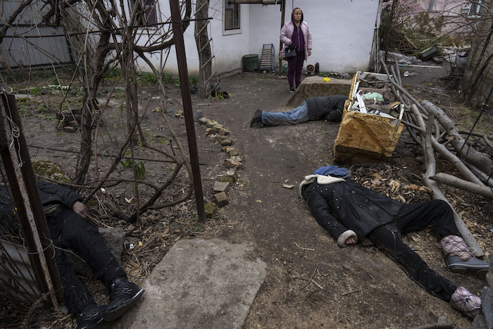 Una mujer permanece de pie junto a tres personas asesinadas en el patio de una casa en Bucha, en las afueras de Kiev, Ucrania, el martes 5 de abril de 2022.