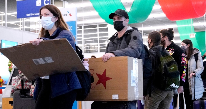 Varios viajeros hacen fila portando mascarillas frente a un mostrador del Aeropuerto Internacional O'Hare en Chicago, el 28 de diciembre de 2021.