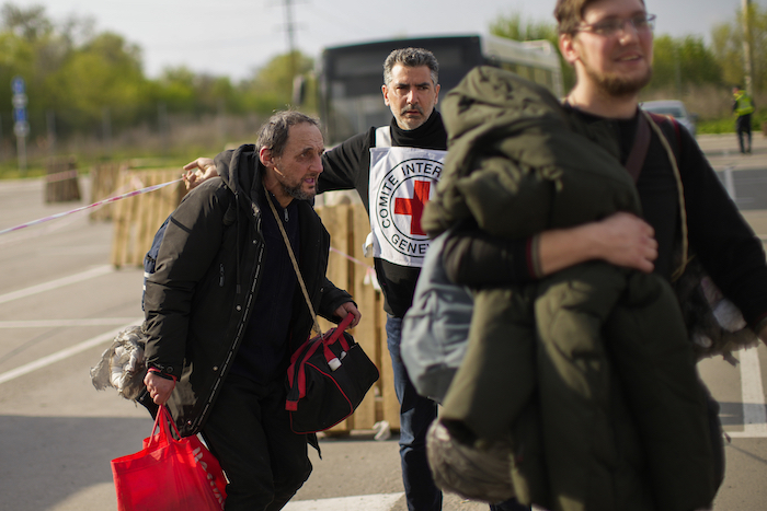 Personal de la Cruz Roja da instrucciones a Serhii Tsybulchenko (izq) y su yerno Ihor Trotsak a su llegada a Zaporiyia (Ucrania) tras la evacuación de unas 100 personas de una planta siderúrgica de Mariúpol (Ucrania). Foto del 3 de mayo del 2022. 