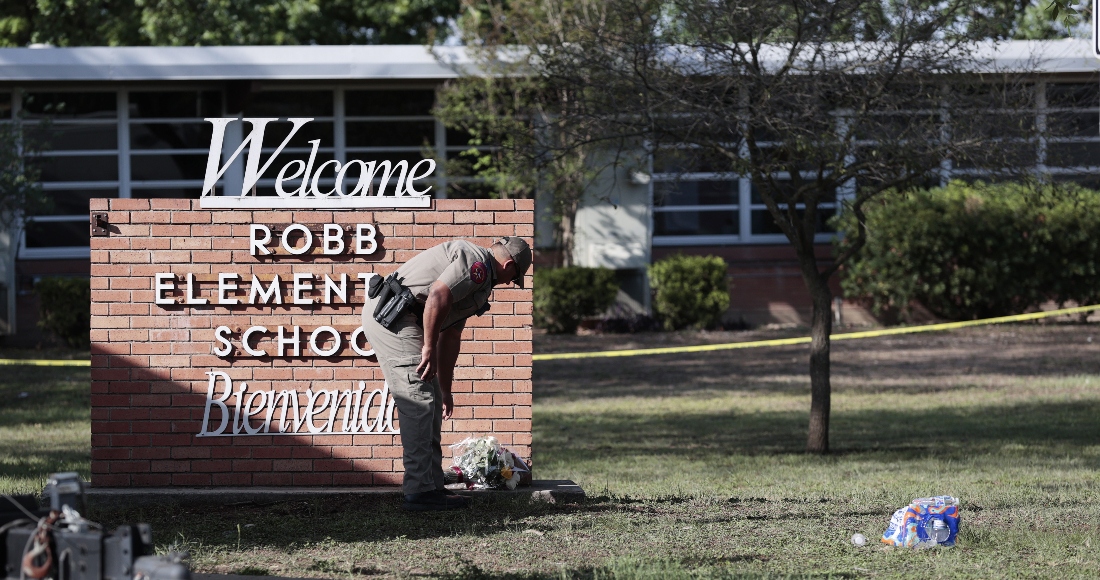 Un policía estatal de Texas coloca flores al pie del letrero de la Escuela Primaria Robb mientras los investigadores continúan trabajando en la escena de un tiroteo masivo en la escuela que mató a 19 niños y dos adultos, según el Gobernador de Texas Greg Abbott en Uvalde, Texas. Estados Unidos, 25 de mayo de 2022.