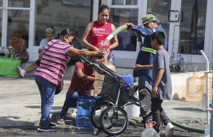 Vecinos llenan garrafas de plástico con agua en un punto de suministro público en Monterrey, México, el 20 de junio de 2022.