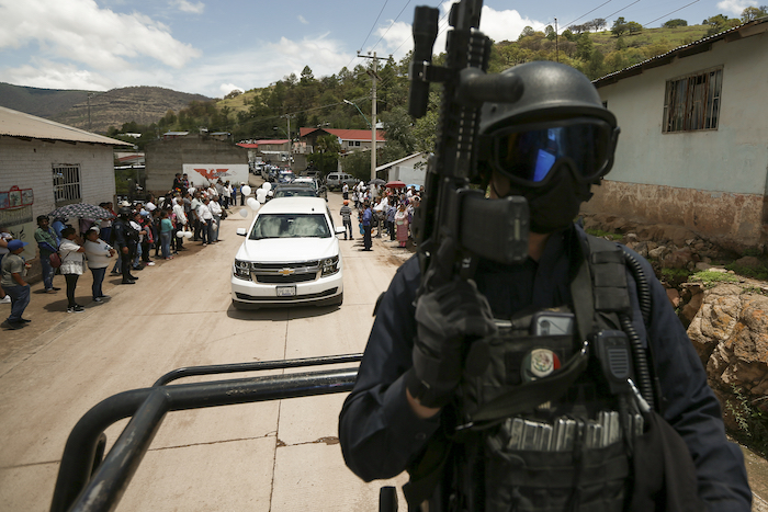 Un policía escolta el cortejo fúnebre de los sacerdotes jesuitas Javier Campos y Joaquín Mora que llegan a Cerocahui, estado de Chihuahua, México, el domingo 26 de junio de 2022.