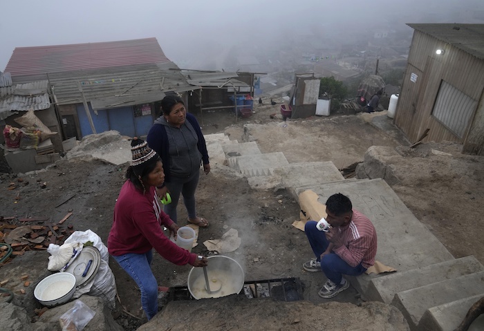 Residentes que juntaron su dinero para comida sirven y comen un desayuno de avena en el área de Ticlio Chico en las afueras de Lima, Perú, el miércoles 1 de junio de 2022.