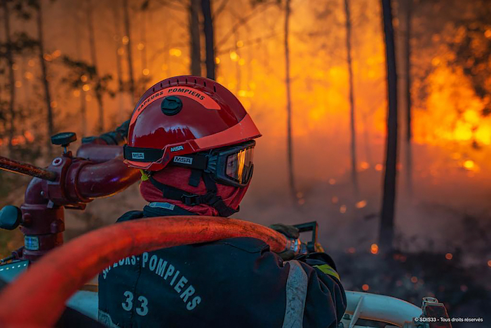 Esta imagen proporcionada por la brigada contra incendios de la región de Gironda (SDIS 33) muestra un bombero trabajando en un incendio forestal en La Test-de-Buch, en el suroeste de Francia, la tarde del lunes 18 de julio de 2022.