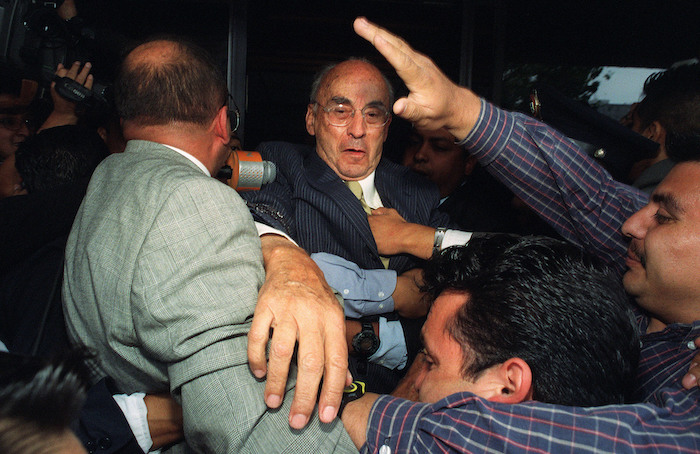 En esta fotografía de archivo, el expresidente mexicano Luis Echeverría, centro, sale de la oficina del fiscal rodeado de guardaespaldas en la Ciudad de México, el 9 de julio de 2002.