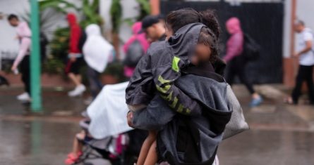 Un migrante cargando a un niño camina bajo una lluvia ligera con un grupo de migrantes cuando salen de la ciudad de Tapachula en el estado de Chiapas, México, la madrugada del lunes 6 de junio de 2022.