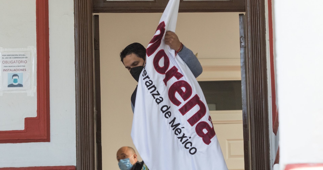 Un hombre acomoda una bandera de Morena durante el anuncio de coalición entre el partido en el poder y Nueva Alianza para el Proceso Electoral 2021.