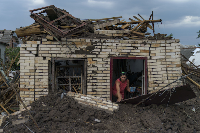 Olga Rudneva, residente de la localidad ucraniana de Druzhkivka, recupera un artículo para un anciano dueño de una casa dañada el jueves 18 de agosto de 2022 luego de que cayeran cohetes rusos en la región de Donetsk, en el este de Ucrania.