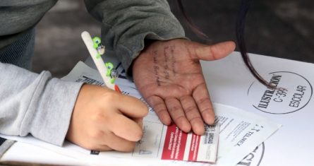 Una joven sin identificar copia los nombres escritos en su mano de Tania Rebollo, contralora de Obras Públicas del Gobierno de Morelos, y de Ulises Bravo Molina, medio hermano del Gobernador, en las papeletas de elección de consejeros estatales durante el proceso electivo interno de Morena.