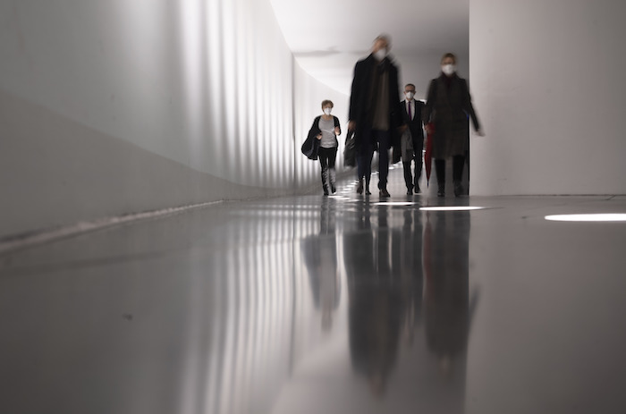 Personas caminando por un túnel en dirección a la sala de plenos antes de un debate sobre el mandato de vacunación contra el coronavirus, en el Parlamento, en Berlín, Alemania, el 26 de enero de 2022.