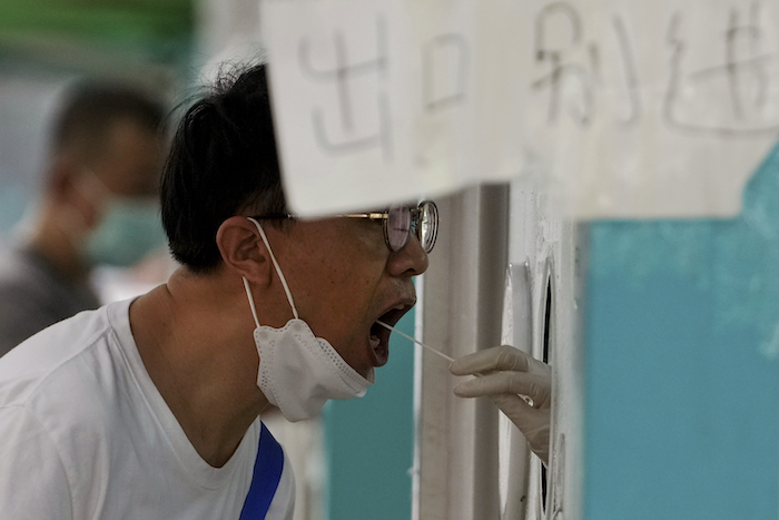 Un hombre pasa una prueba rutinaria de COVID-19 en un centro de pruebas en Beijing, el domingo 7 de agosto de 2022.