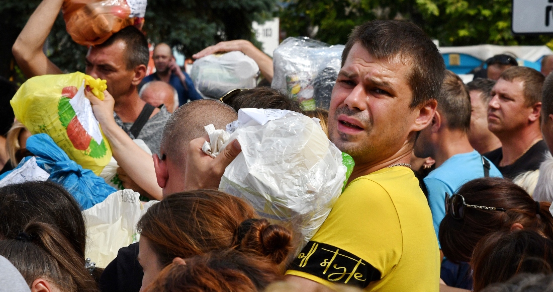 Residentes locales, muchos de los cuales huyeron de la guerra, se reúnen para entregar donativos como medicamentos, ropa y pertenencias personales a sus familiares en los territorios ocupados por Rusia, el domingo 14 de agosto de 2022, en Zaporiyia, Ucrania.