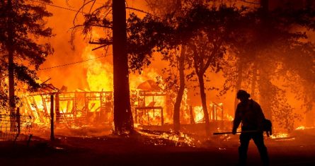 Un bombero combate las llamas que destruyen una casa en Plumas County (California), el 24 de julio del 2021.