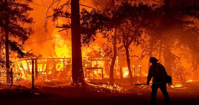 Un bombero combate las llamas que destruyen una casa en Plumas County (California), el 24 de julio del 2021.