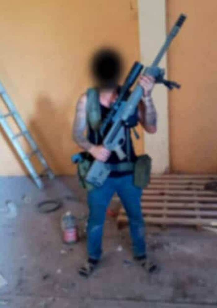 Carlos sosteniendo un arma de gran calibre después de llegar a Tierra Caliente, México.