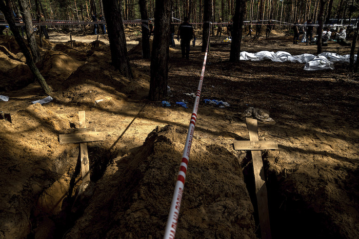 En esta fotografía pueden apreciarse tumbas sin identificar de soldados y civiles ucranianos en un cementerio durante una exhumación, el sábado 17 de septiembre de 2022, en la zona recién retomada de Izium, Ucrania. 