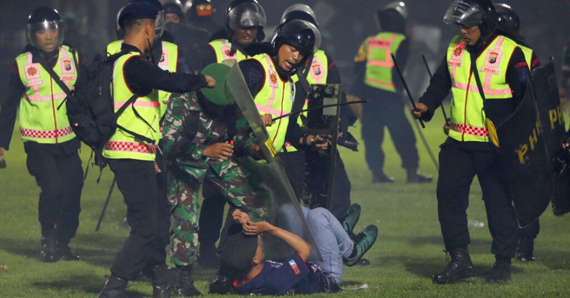 Agentes de seguridad detienen a un aficionado durante una serie de trifulcas en un partido de futbol, el sábado 1 de octubre de 2022, en Malang, Indonesia.