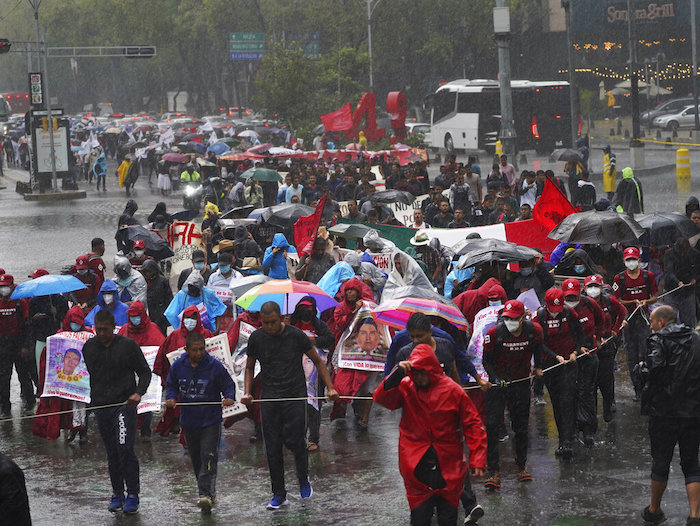 Amigos y parientes que buscan justicia para 43 estudiantes de la normal rural de Ayotzinapa que desaparecieron marchan bajo la lluvia durante una protesta, el viernes 26 de agosto de 2022, en la Ciudad de México.