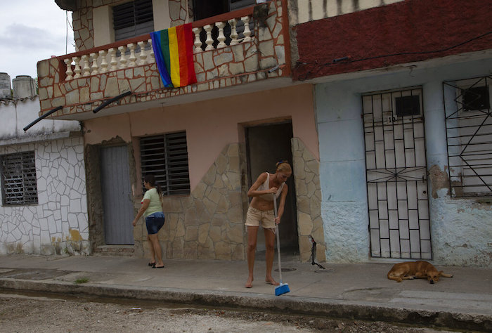 Con una bandera del orgullo sobre su balcón, Lisset Díaz Vallejo barre la acera frente a su casa la tarde del día de su boda en Santa Clara, Cuba, el viernes 21 de octubre de 2022.