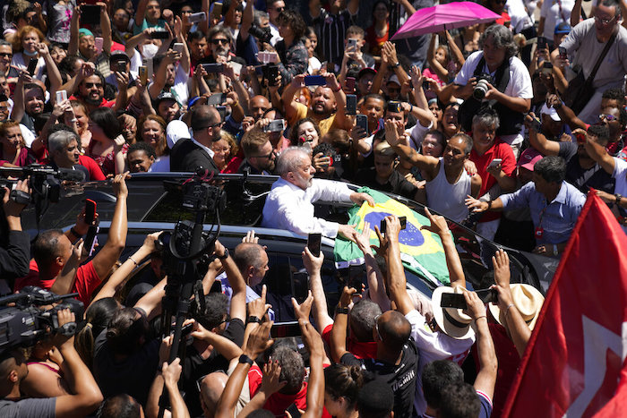 El expresidente Luiz Inácio Lula da Silva, al centro, que aspira a ser reelegido, sostiene una bandera de Brasil rodeado por simpatizantes tras depositar su voto en la segunda ronda electoral, el domingo 30 de octubre de 2022, en Sao Paulo, Brasil.