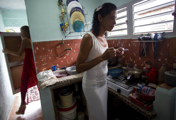 Liusba Grajales fuma en la cocina mientras su prometida Lisset Díaz Vallejo sale del baño, antes de irse a la notaría para casarse en Santa Clara, Cuba, el viernes 21 de octubre de 2022.