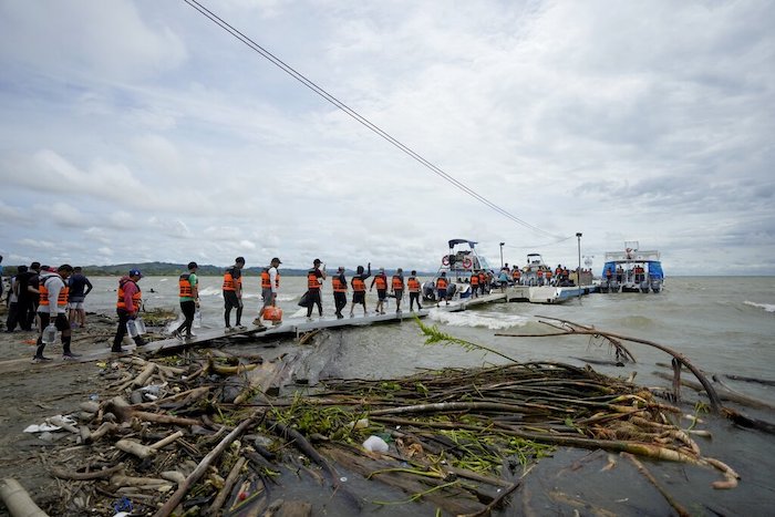 Migrantes venezolanos caminan hacia una lancha que los llevará a Acandi, desde Necocli, Colombia, el 13 de octubre de 2022.