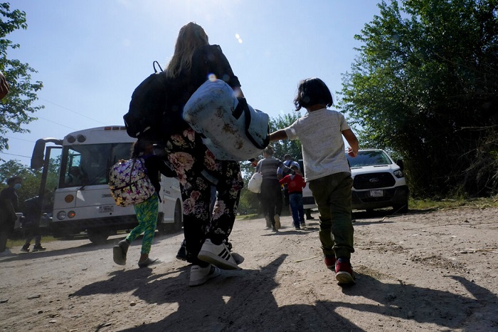 Una familia de migrantes venezolanos se dirige hacia un autobús de la Patrulla Fronteriza después de que cruzaran con otras personas de México hacia Estados Unidos y se entregaran a las autoridades, el miércoles 17 de junio de 2021, en Del Río, Texas.