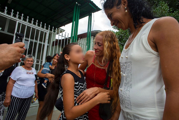 Laura Gil, en el centro, con su madre Lisset Díaz Vallejo, al centro, frente a la notaría después de que su madre se casara con su pareja, Liusba Grajales, a la derecha, en Santa Clara, Cuba, el viernes 21 de octubre de 2022.